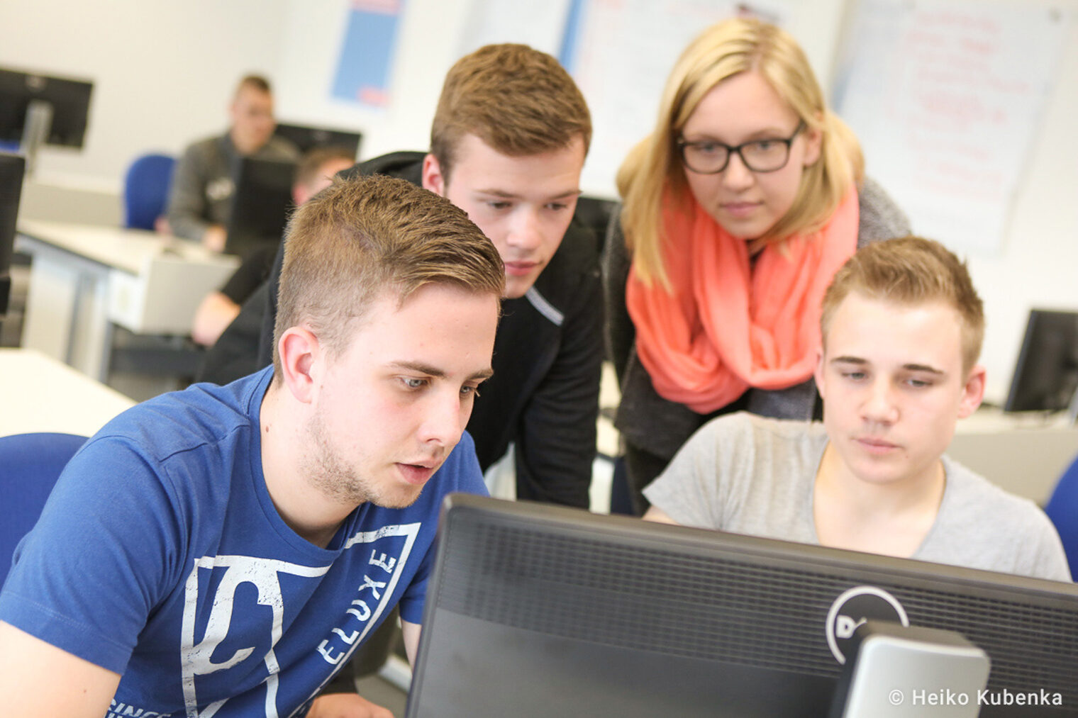 Personen vor Computer-Bildschirm In einem Unterrichtsraum stehen vier Personen und gucken gemeinsam auf einen Computer-Bildschirm.