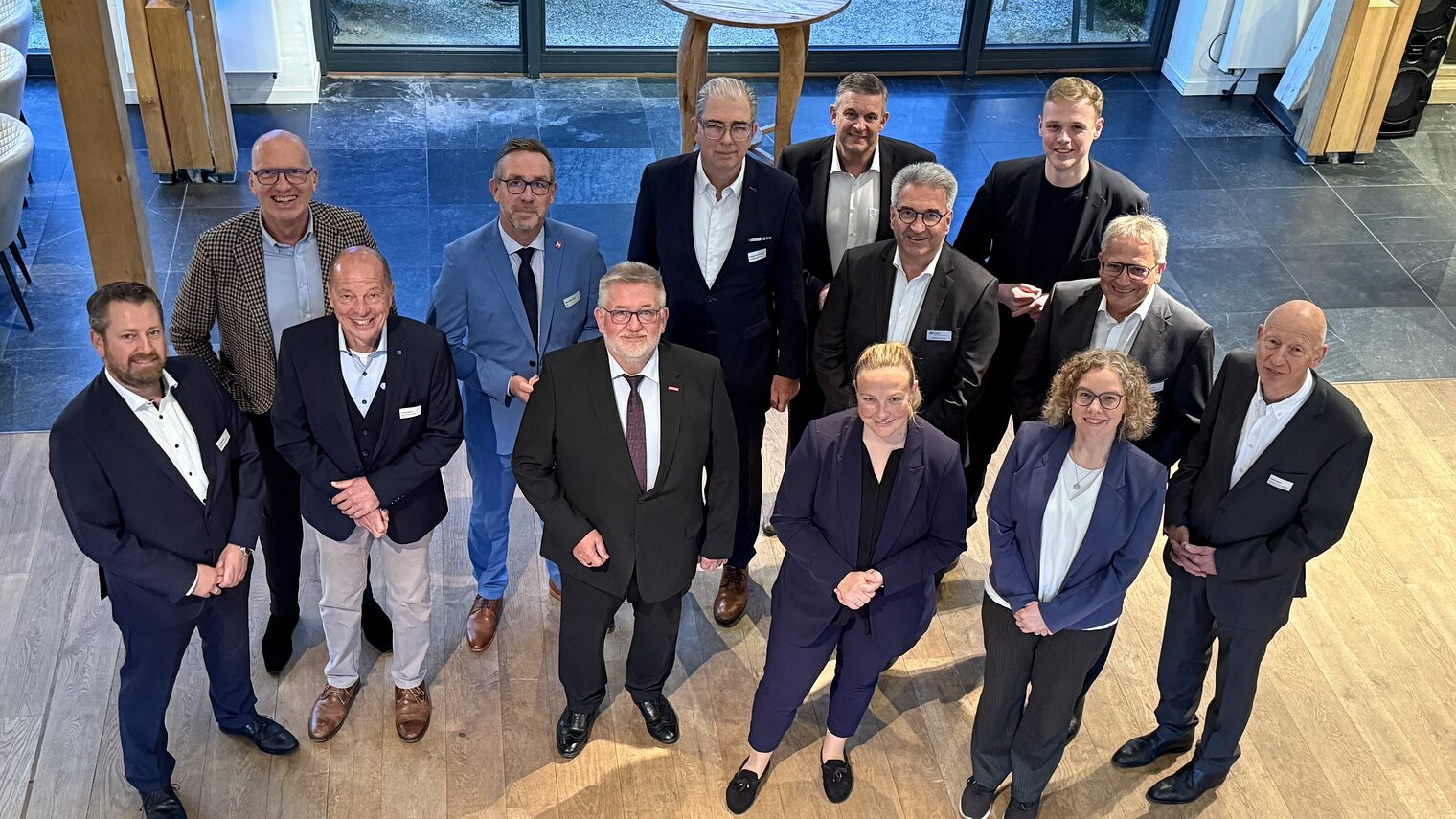 Gruppenfoto von Teilnehmer:innen des Parlamentarischen Abends der Wirtschaft 2025 in Businesskleidung vor moderner Kulisse