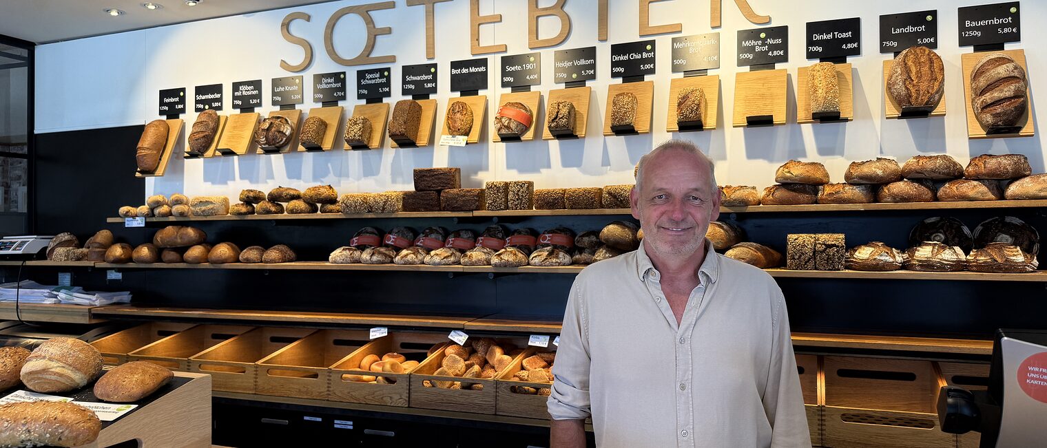 Bäckereiinhaber Frank Soetebier vor seiner Ladentheke in Winsen (Luhe) und gleichnamigen Schriftzug