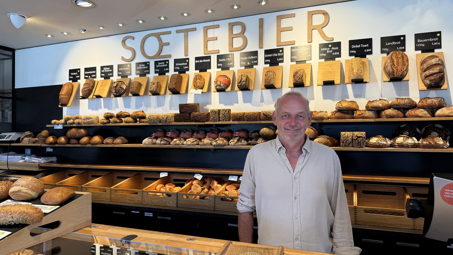 Bäckereiinhaber Frank Soetebier vor seiner Ladentheke in Winsen (Luhe) und gleichnamigen Schriftzug